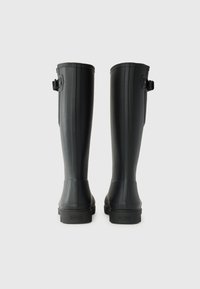 Black rubber knee-high boots with a textured surface, featuring vertical ribs and an adjustable buckle strap on the side.