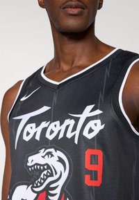 Čierny basketbalový dres s nápisom "Toronto" v bielom písme, číslom 9 v červenej farbe a veľkým logom dinosaura, s bielymi akcentmi a sieťovanou textúrou.