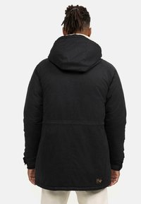 Chaqueta negra aislante con capucha, que cuenta con un cuello forrado de polar, tejido texturizado y un parche de logo en la parte baja de la espalda.