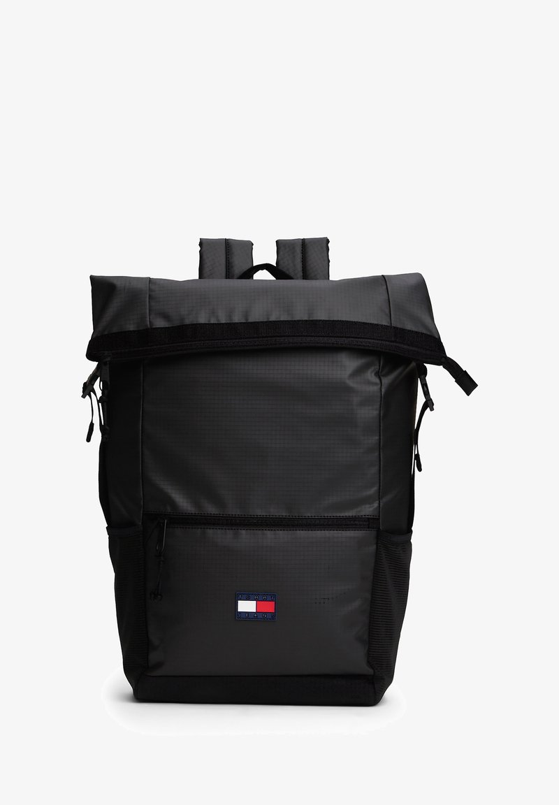 Musta, kestävistä kankaista valmistettu roll-top-reppu, jossa on etutasku vetoketjulla, säädettävät hihnat ja logoplässi alareunassa.