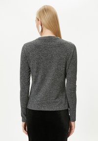 Ciemnoszary longsleeve z delikatnym metalicznym połyskiem, okrągłym dekoltem i dopasowanym krojem. Miękka tekstura, minimalistyczny design i brak widocznych wzorów.