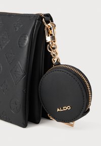 Mustruge musta k�äekott, millel on reljeefsed mustrid ja kuldne riistvara, koos ümmarguse mündikoti, mis on kinnitatud ahela külge. Tekstureeritud viimistlus ja tõmblukuga sulgemine.