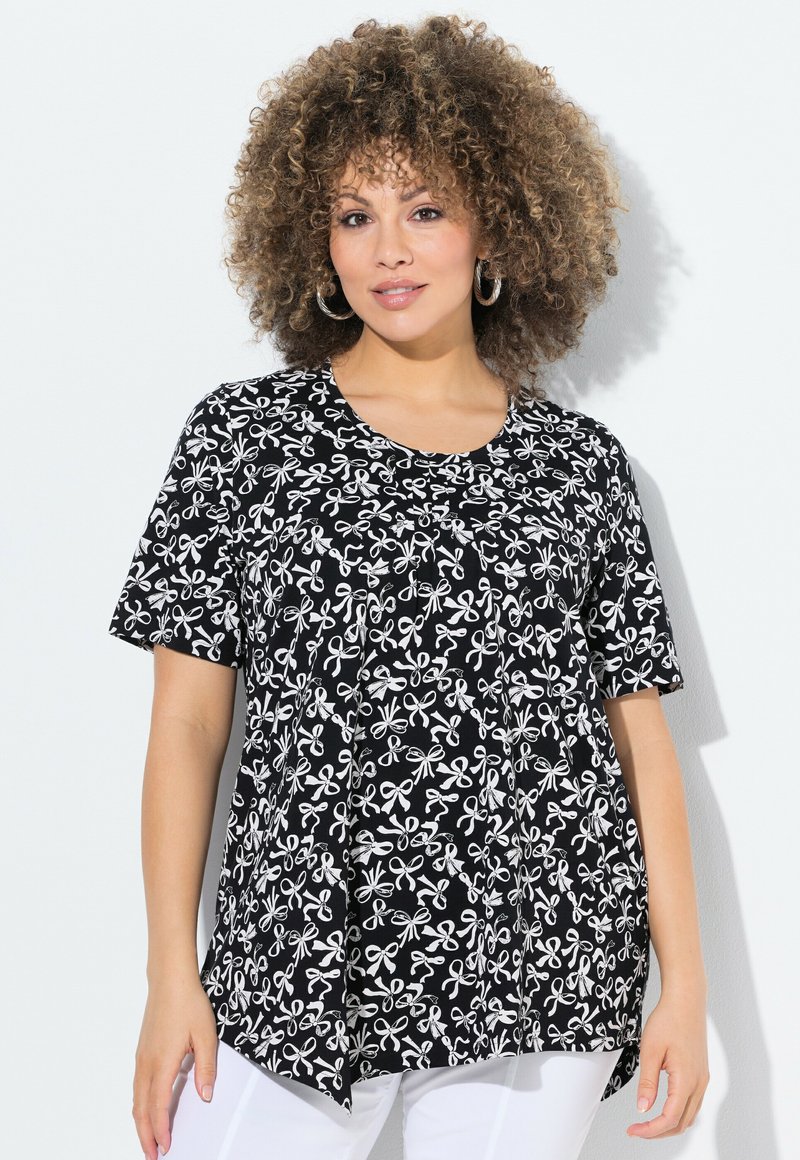 Schwarze Bluse mit einem weißen Blumen- und Schleifenmuster, kurzen Ärmeln, einem runden Ausschnitt und einem lockeren Schnitt mit abgerundetem Saum.