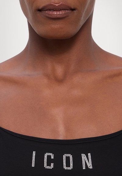 Black sleeveless top featuring rhinestone embellishment spelling "ICON" in capital letters. Smooth fabric texture with a fitted design.