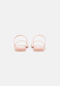 Sandales pêche avec un design à deux fines brides. Fini brillant, semelle plate légèrement texturée. Vue de l'arrière, mettant en valeur le style minimaliste.