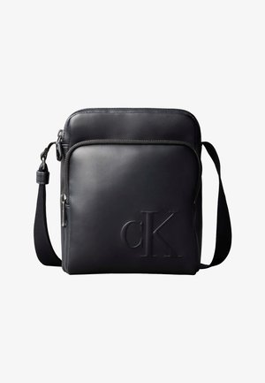 Fekete, kompakt, keresztpántos bőrtáskán elülső cipzáras zseb és dombornyomott "cK" logó található, állítható szövetpánttal.