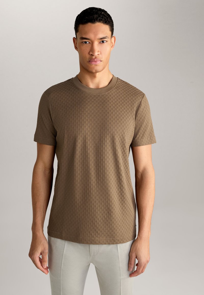 Braunes strukturiertes Kurzarm-T-Shirt mit Rundhalsausschnitt, das ein geometrisches Muster und einen lockeren Schnitt aufweist. Kombiniert mit hellen Hosen.