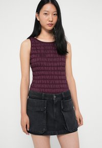 Μωβ εφαρμοστό τοπ με υφασμάτινες πτυχώσεις, συνδυασμένο με μαύρη τζιν μίνι φούστα που διαθέτει μεγάλες τσέπες και κλείσιμο με κουμπί.