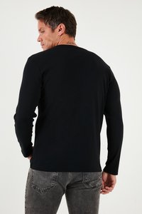 Juodas ilgomis rankovėmis marškinėliai, pagaminti iš švelnaus medvilnės, su apvalia iškirpte ir prigludusiomis rankovėmis. Derinami su šviesiai pilkais sunaikintais džinsais.