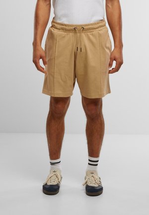 Kaki shorts laget av myk stoff, med elastisk midjebånd og snore, sidelommer og en avslappet passform, kombinert med sneakers.