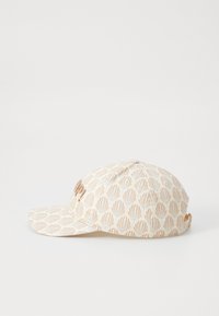 Hatt i kremfarge med et mønster av lysebrune og blå skjellformer. Har en buet skjerm og et brodert logo på fronten.