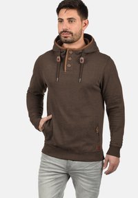 Bruine hoodie met een knoopsluiting, aantrekkoorden, zijzakken en contrasterende accenten. Gemaakt van zachte stof, met een relaxte pasvorm.