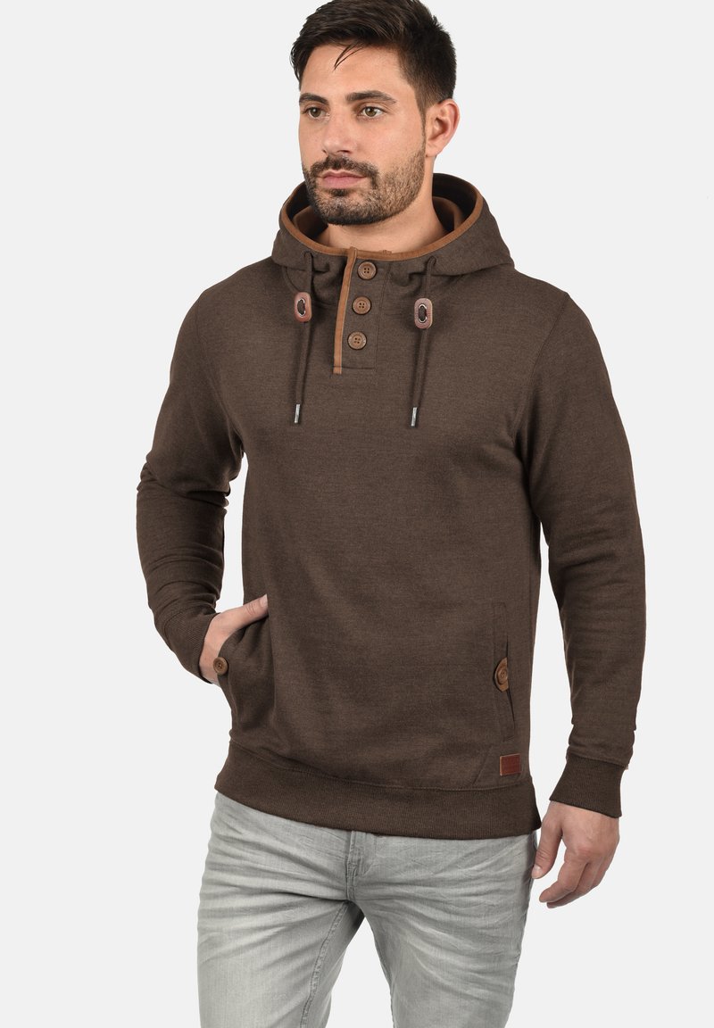 Bruine hoodie met een knoopsluiting, aantrekkoorden, zijzakken en contrasterende accenten. Gemaakt van zachte stof, met een relaxte pasvorm.