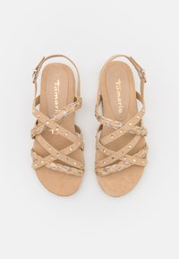 Beiga mockaskor med flätade remmar, prydda med små dekorativa rhinestenar och en justerbar vristrem. Storlek 37, öppen tå.