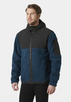 Fleece- en nylonjack met een zwart bovenstuk en een donkergroen onderstuk. Voorzien van een rits aan de voorkant en een ritszak op de mouw.