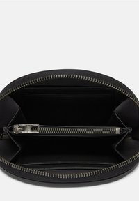 Portafoglio in pelle nera con chiusura a zip, esterno texturizzato e più slot per carte all'interno. Interno foderato in tessuto nero uniforme.