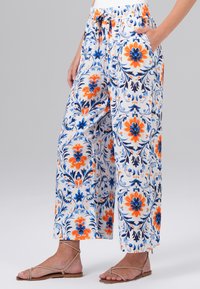 Brede broek met een bloemenpatroon in oranje, blauw en wit. Gemaakt van lichtgewicht stof met een elastische tailleband en zijzakken.