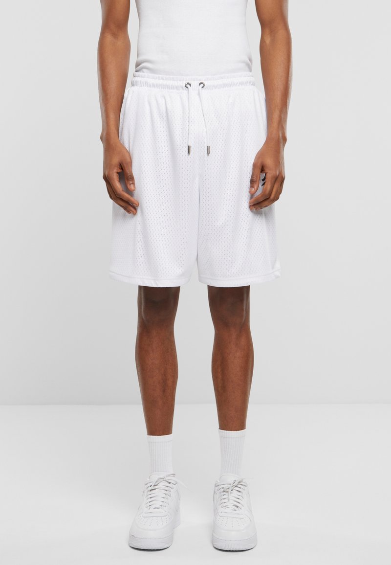 Hvite, nett basketballshorts med elastisk liv og snor. Har lommer og løs passform, kombinert med hvite sneakers og sokker.