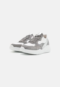 Gray suede and white leather sneaker with a rounded toe, lace-up design, and metallic accent on the heel. Chunky rubber sole.