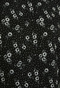 Tecido preto com padrão floral branco e pequenas bolas brancas. Apresenta contornos detalhados de flores com folhas, conferindo uma aparência texturada.