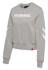 Sweat-shirt gris à manches longues avec col rond, logo "HUMMEL" et bandes chevrons blanches sur les manches, poignets et ourlet côtelés, et une étiquette rouge près du bas.