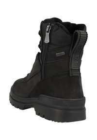 Zwarte enkelboot met een bovenwerk van suede en synthetisch materiaal, voorzien van een gestructureerde afwerking, ritsluiting en stevige rubberen zool. Verzorgd met een trekband.