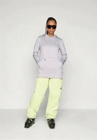 Ανοιχτό γκρι φούτερ με κουκούλα και μπροστινή τσέπη, σε συνδυασμό με κίτρινες cargo παντελόνες. Μαύρες σκιώνες ολοκληρώνουν την εμφάνιση. Λείος υφασμάτινος ιστός, casual σχεδίαση.