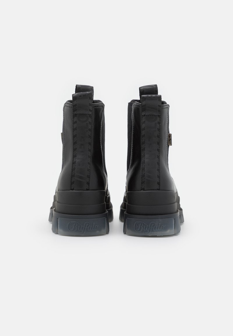 Schwarze Knöchelstiefel aus glattem Leder, ausgestattet mit einer dicken, strukturierten Sohle und auffälligen elastischen Seiteneinsätzen. Logo geprägt an der Ferse.