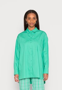 Camisa azul-turquesa com botões, feita de um tecido leve, com colarinho clássico, um único bolso no peito e um ajuste solto.