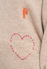 Maglione beige con una morbida texture, decorato con ricami di foglie arancioni e testo "MOSCHINO" color crema circondato da un cuore rosso tratteggiato.
