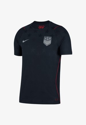 Maillot de sport bleu marine foncé à manches courtes avec un motif étoilé subtil, écusson de l'équipe de football américaine sur la poitrine, logo Nike Swoosh et fines bordures rouges sur les côtés.