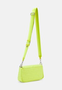 Borsa a mano rettangolare di un vivace verde neon, con un motivo circolare testurizzato, accessori metallici e una tracolla regolabile.