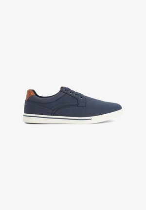 Sneakers blu navy con tessuto strutturato, dettaglio in pelle marrone sul tallone, suola in gomma bianca e design tradizionale con lacci.