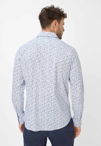 Camicia a maniche lunghe di colore azzurro chiaro con un piccolo motivo floreale. Presenta un colletto classico e polsini con bottoni, realizzata in tessuto leggero.