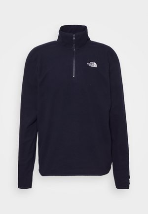 Fleece-trøje i marineblå med halvlange lynlås i kraven, med The North Face-logo på venstre bryst og lange ærmer. Blød tekstur.