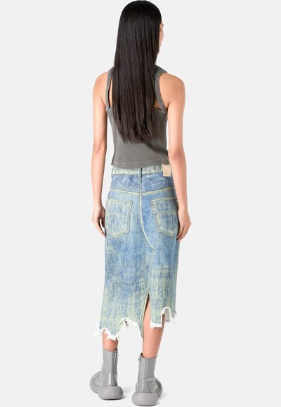 Gonna di denim blu chiaro con orlo sfilacciato, due tasche posteriori e una leggera apertura. Abbinata a un top grigio senza maniche e stivali alla caviglia grigi.