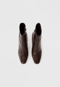 Bottes chevilles en cuir marron avec un bout carré, dotées d'une fermeture éclair sur le côté et d'une texture lisse.