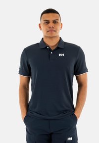 Polo navy con diseño de cuello, logo de marca en el pecho y ribete blanco en las mangas, fabricado con una tela texturizada y transpirable.
