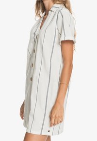 Robe chemise à manches courtes en tissu léger, blanche avec des rayures verticales bleu marine, à revers, avec un col et des poches latérales.