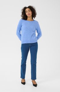 Light blue knitted sweater with a round neckline, paired with dark blue straight-leg jeans and black pointed-toe heels.