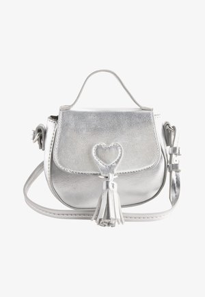 Pequeño bolso plateado con asa superior, correa de hombro desmontable, cierre en forma de corazón y detalle de borla en la solapa frontal.