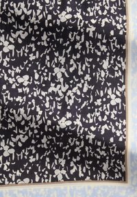 Blauw-wit patroon op stof met abstracte bloemvormen tegen een donkere achtergrond, omrand door een lichtblauwe rand. Zachte, gladde textuur.