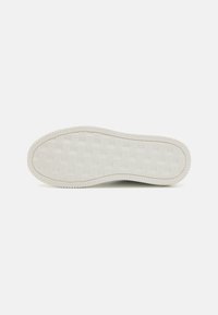 Sole di sneakers in gomma bianca con una presa texture e pattern, bordi rialzati e piccoli disegni quadrati sparsi.