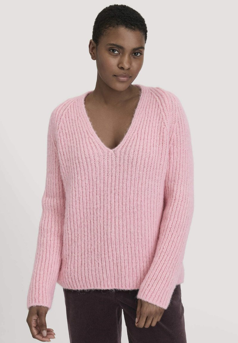 Hellrosa gestrickter Pullover mit V-Ausschnitt, geripptem Muster und langen Ärmeln. Weiches, gemütliches Material mit einer entspannten Passform.