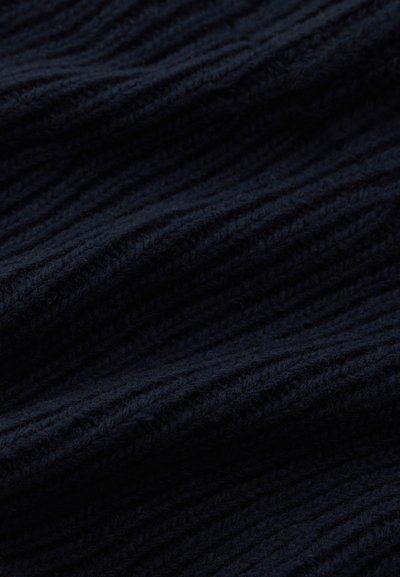 Imagem em close-up de um tecido azul marinho escuro com uma textura de malha grossa e canelada, apresentando fibras de lã macias e felpudas.