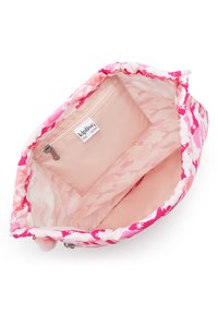 Inuti en rosa tygpåse med blommönster, utrustad med en dragkedjeficka och Kipling-logotyp. Mjuk textur och rund form.