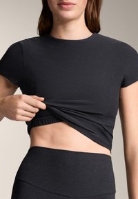 Ciemnoszary dopasowany krótki top z krótkimi rękawami, z marszczonym elastycznym dołem i miękką, gładką fakturą, połączony z wysokim stanem spodni.