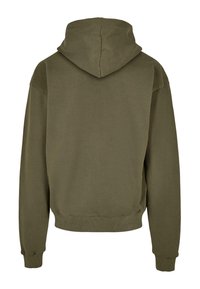 Olivově zelená mikina s kapucí, která má klokaní kapsu, hřejivé manžety a lem, a měkkou strukturu. Kapuce je lehce oversized pro uvolněný střih.