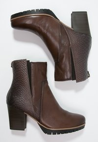 Brown leather ankle boots with a textured dark brown snake pattern on the sides, chunky heel, and rubber soles for traction.