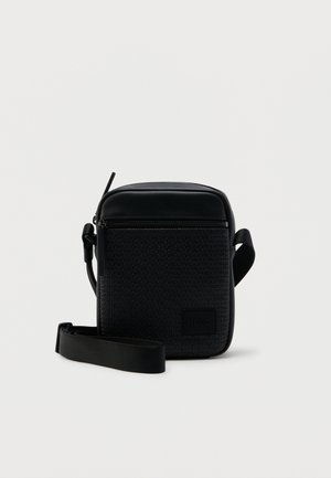 Kompaktne must õlakott reguleeritava rihmaga, esiküljel tõmblukuga tasku ja reljeefse korduva logomustriga, millel on "HUGO" märk.